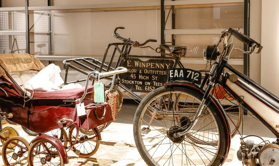 A space in the open store, containing a vintage motorcycle and pram.