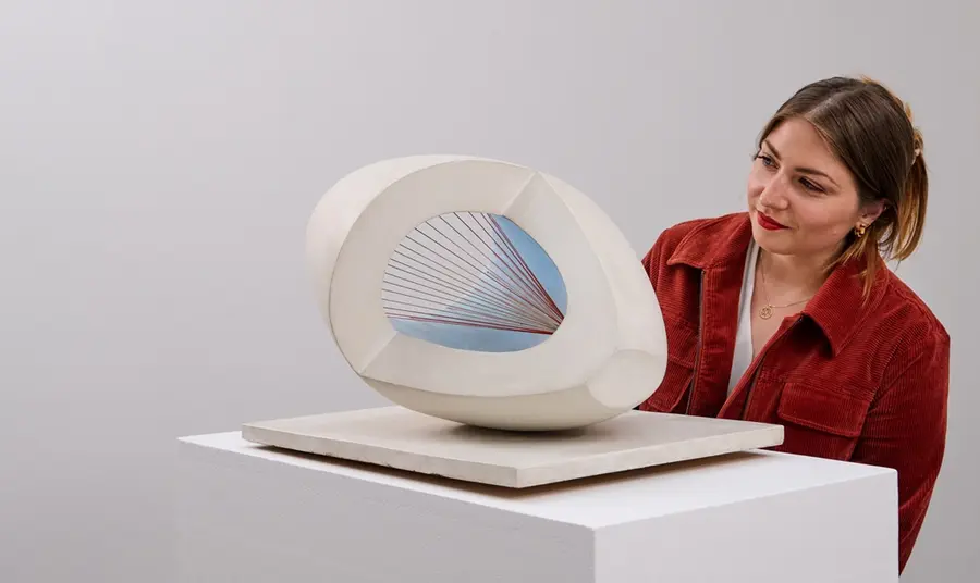 A young woman looks at a sculpture by Barbara Hepworth.