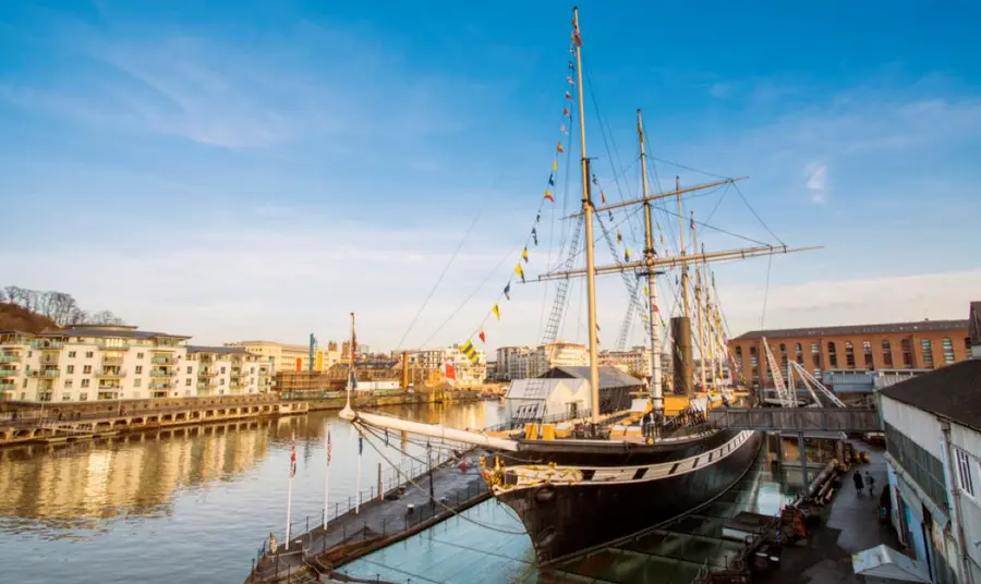 SS Great Britain sits in dock on Bristol waterfront, on a bright and sunny day.