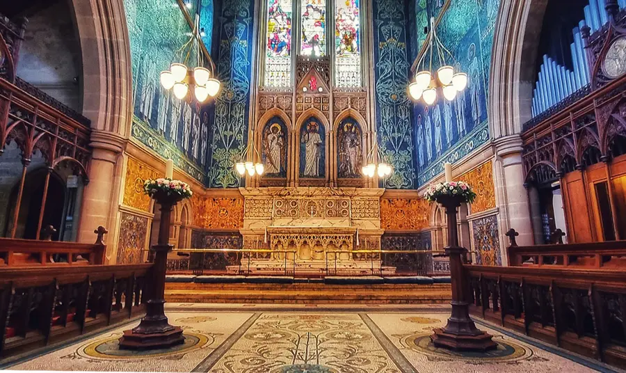 An interior view of a church altar with stained glass windows in the background
