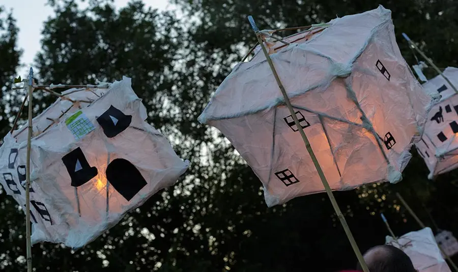 Two paper lanterns in the shape of houses in an outdoor parade