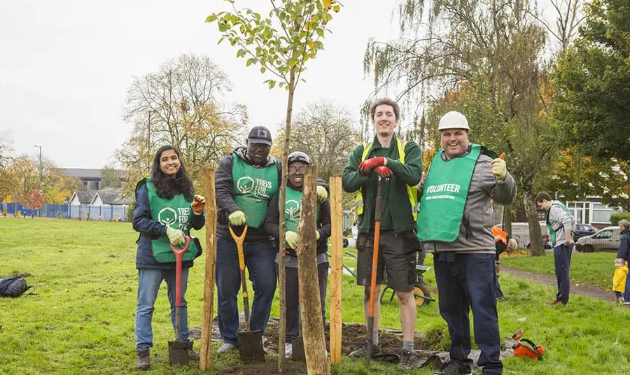 A group of Trees for Cities volunteers pose for the camera during a tree-planting session