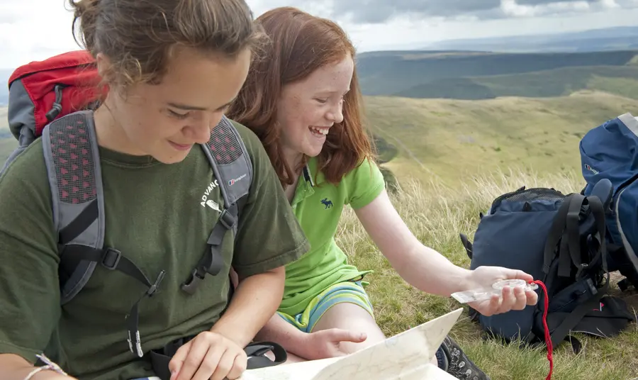 Two people looking at a map and compass in the hills