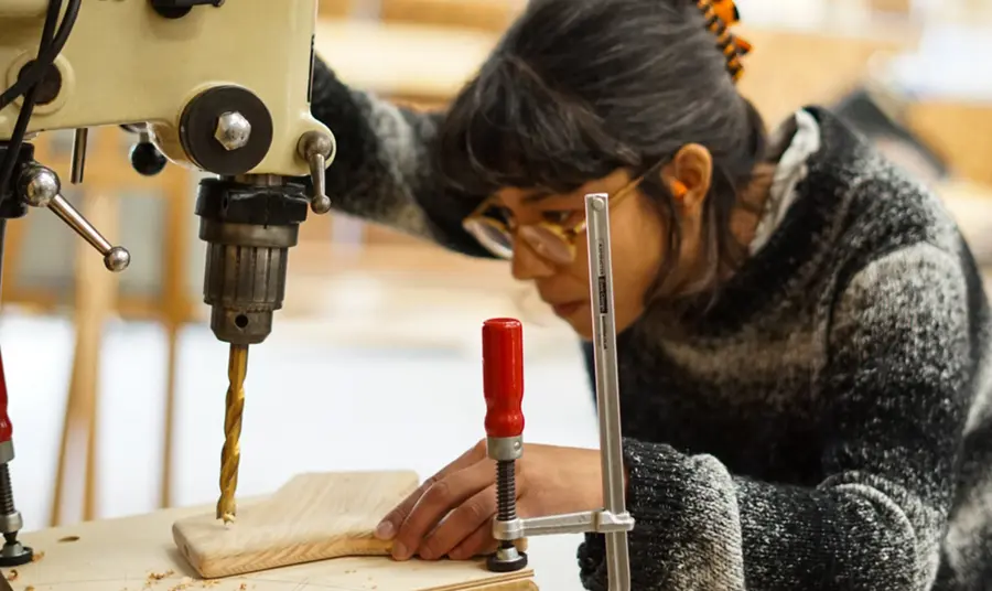 A woman drilling a hole in wood with a power tool