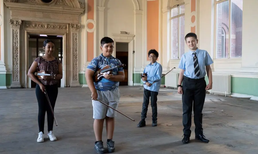 Young musicians in Canada House, Sheffield. Four young musicians stand together in a large room within Canada House, prior to the restoration.