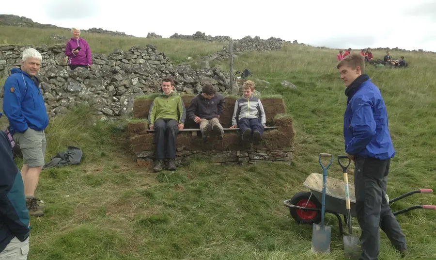 Young people sitting on an outdoor bench made from turf