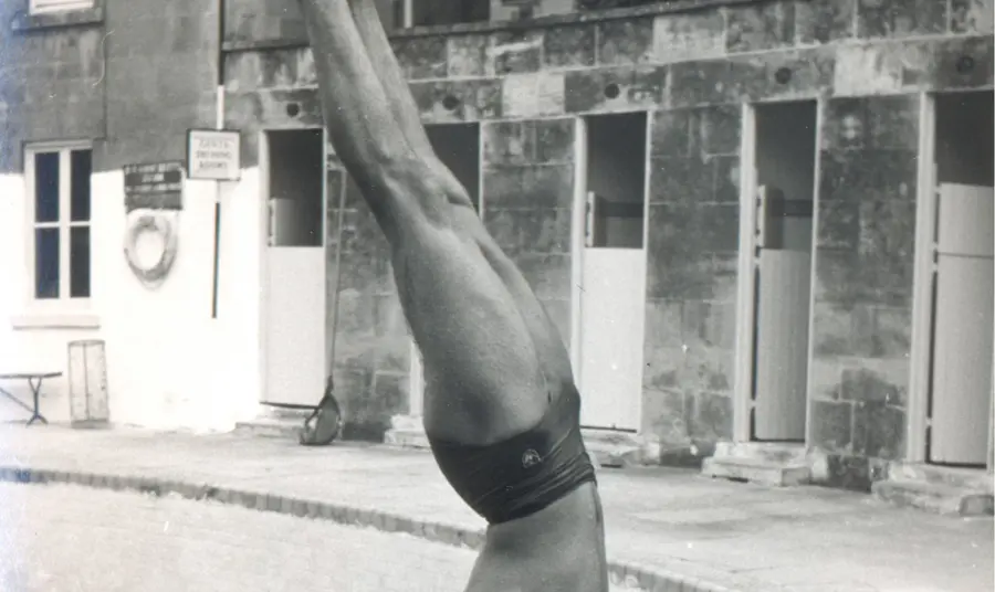 Man doing a handstand by a swimming pool