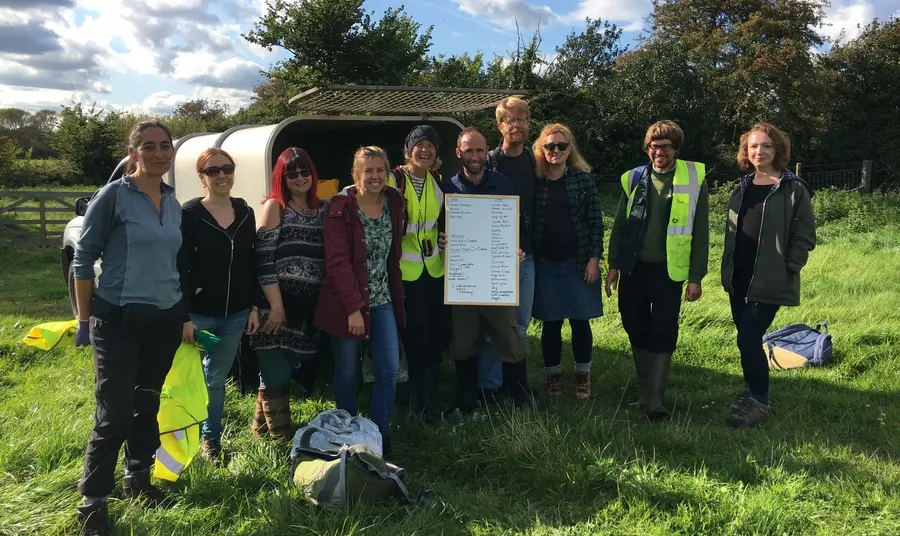 People stand in a field with a sign