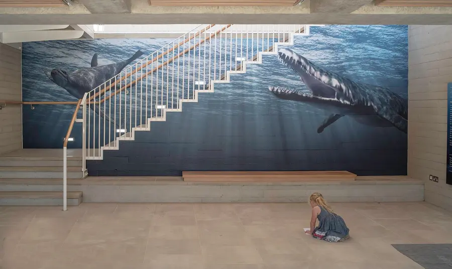 A little girl in front of the image of Jurassic marine life