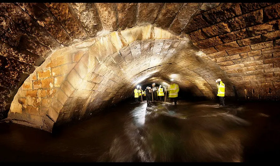 People inspecting the River Roch's medieval bridge