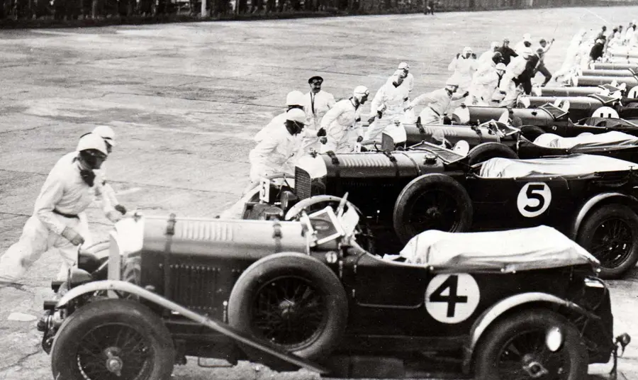 Cars ready to race at Brooklands in 1930 with the Vickers aircraft factory in the background