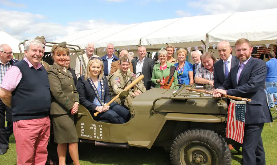 People stand near a military jeep