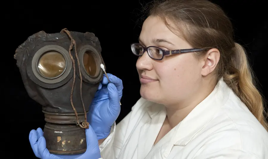 Conservation intern Louise Stewart cleaning a gas mask for the exhibition