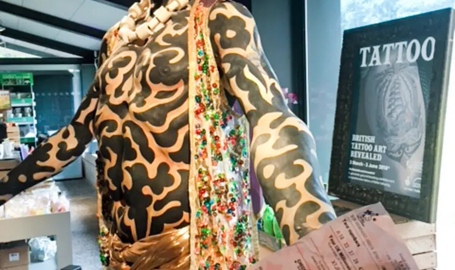 Free tattoo exhibition for National Lottery players Omi, part of the exhibition, with National Lottery ticket