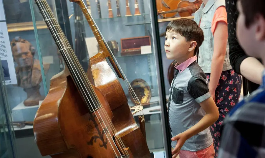 Child looking at a display of instruments in the Royal College of Music Museum Royal College of Music Museum: child looking at instruments