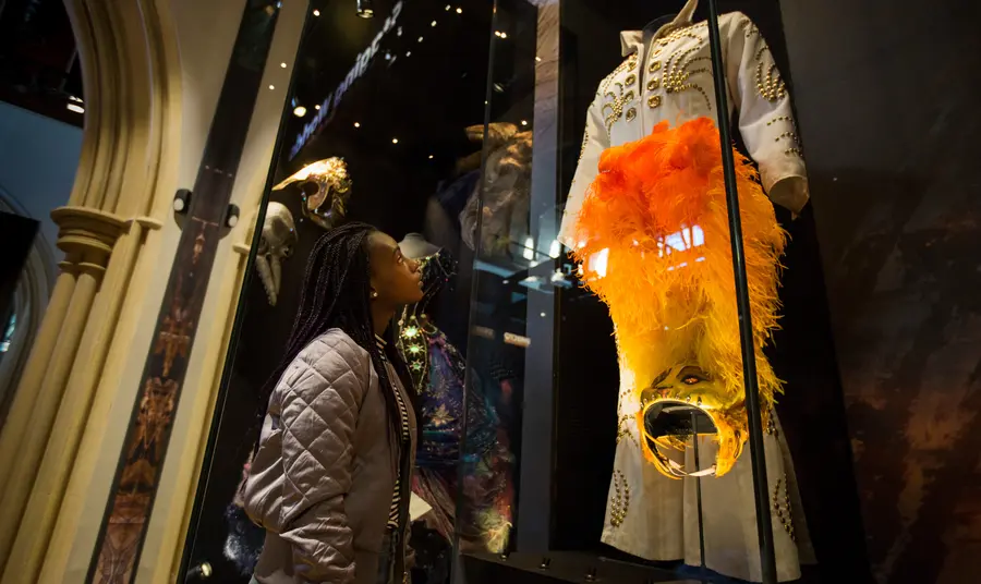 A girl looking at some clothing at The Play’s The Thing exhibition