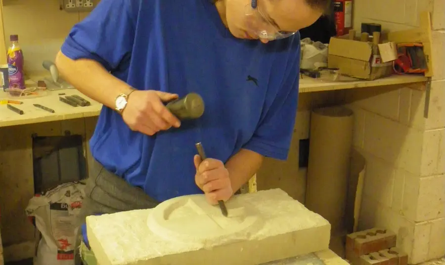 Young person putting their newly gained stone carving skills into practice