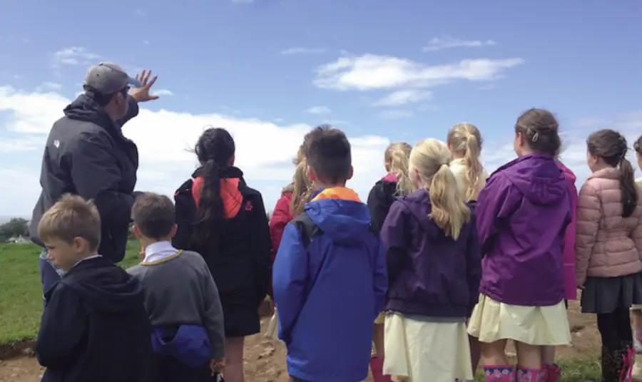 Children listening to a talk about the archaeological site