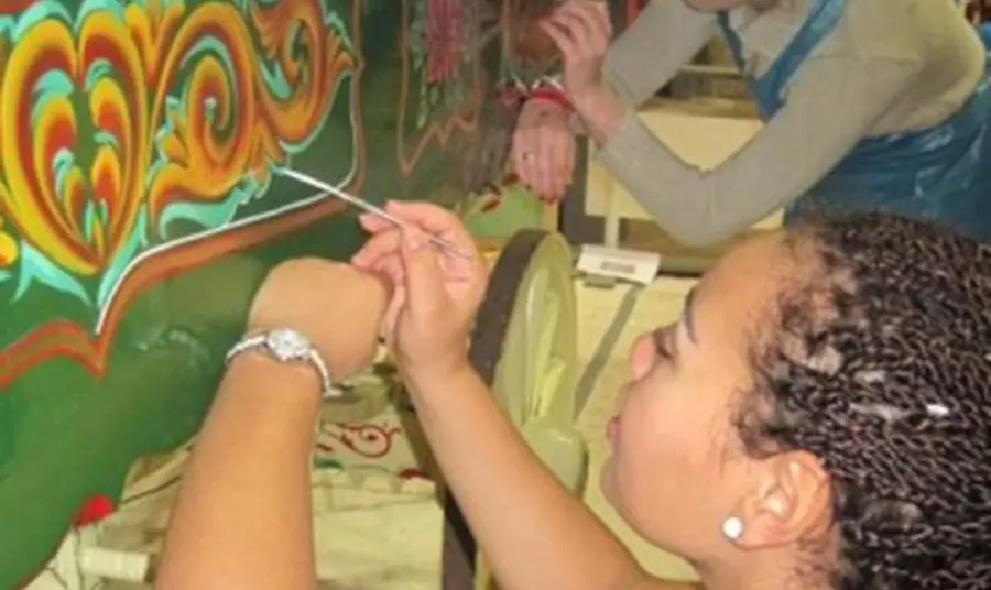 A person painting a colourful design on a wagon