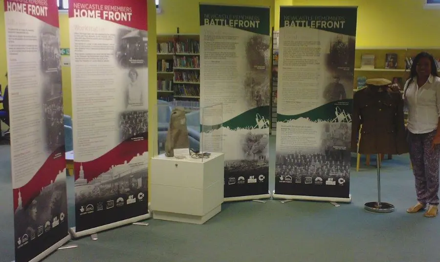 A woman stands by four pull up displays, a model uniform on a mannequin and a glass case containing replica first world war objects