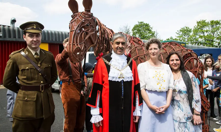 People standing in front of a puppet war horse