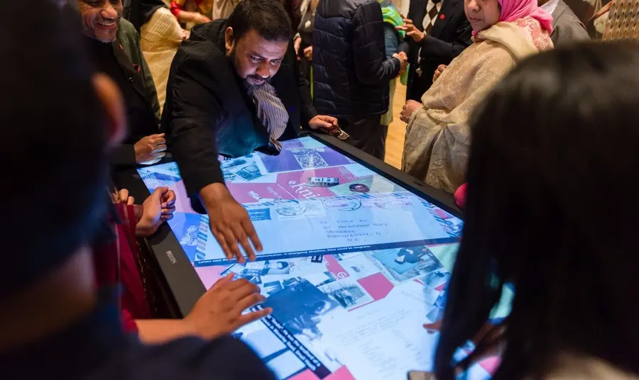A group of people looking at historic photos on a touch table