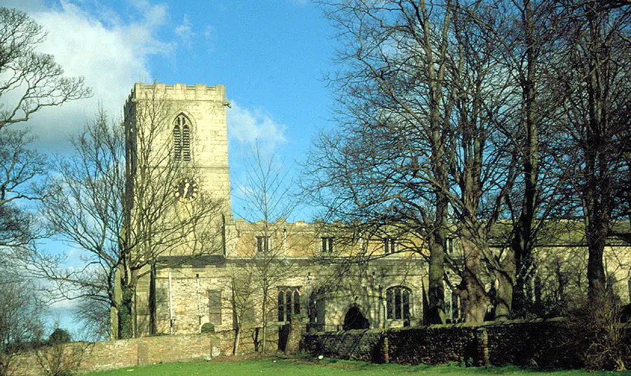 A medieval stone church with trees in front.