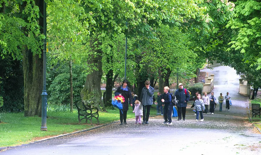 Adults and children walk in Tollcross Park