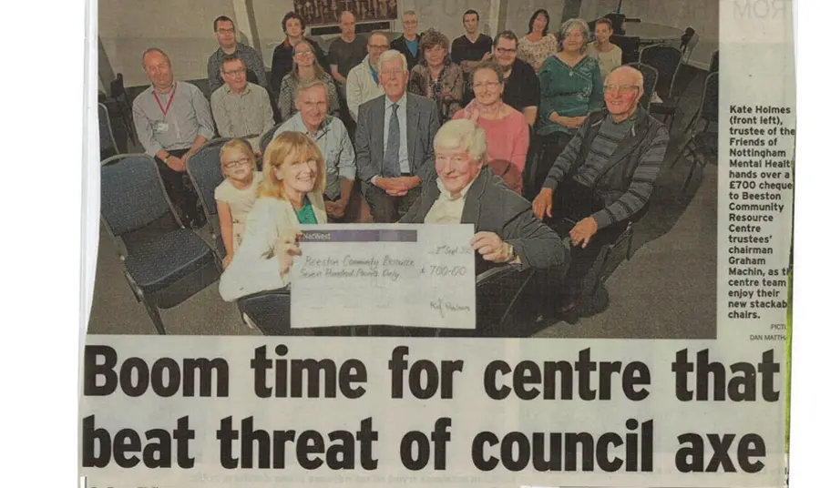 A newspaper clipping: the headline reads 'Boom time for centre that beat threat of council axe' and the photo shows a group of people sitting holding a cheque