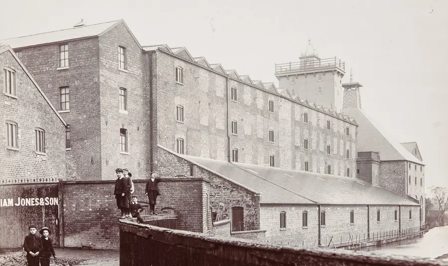 A black and white historic image of the front of the site with children standing in front of it