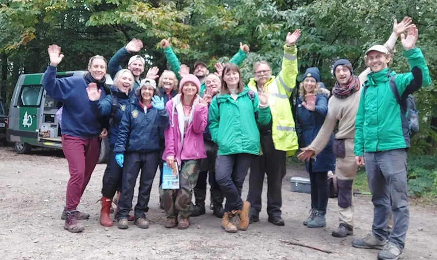 a group of archaeology volunteers wave at the camera
