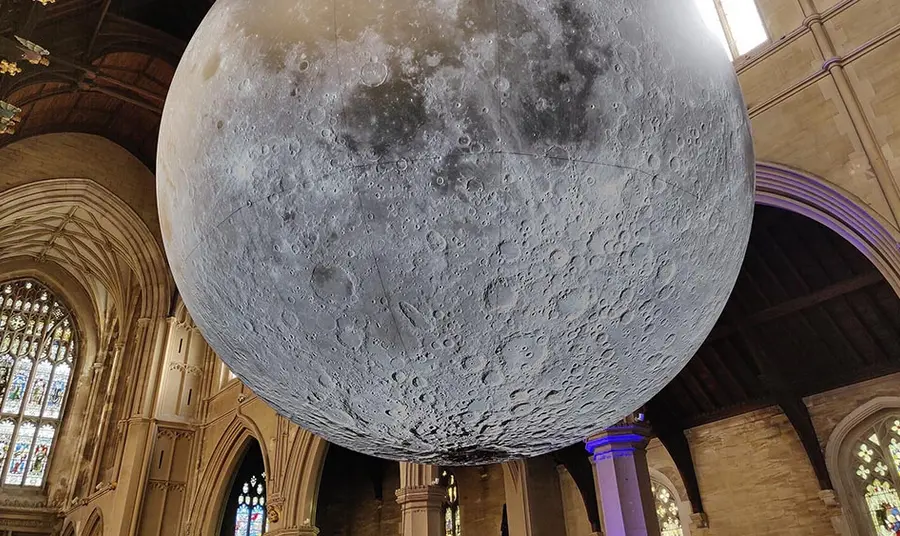 An huge moon sculpture hangs in a small church