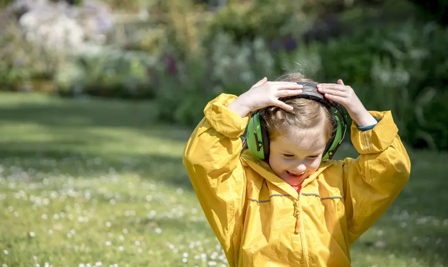 Image of child with headphones on head wearing yellow waterproofs