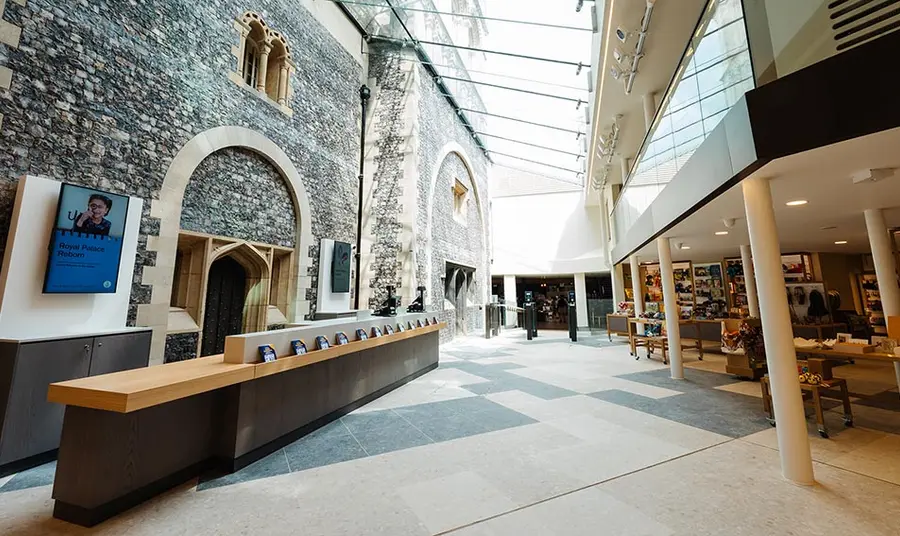 A large atrium with a castle's stone wall on the left and shop and restaurant on the right