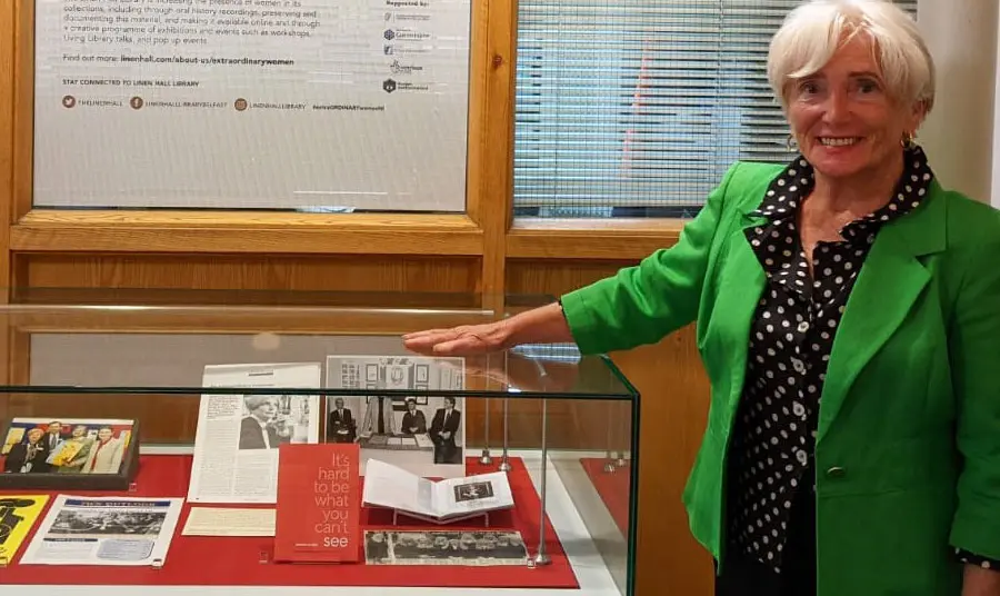 A woman standing next to an exhibition display case, with her hand on top of the case