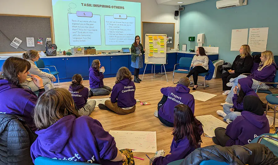 A group of student volunteers listening to a presentation