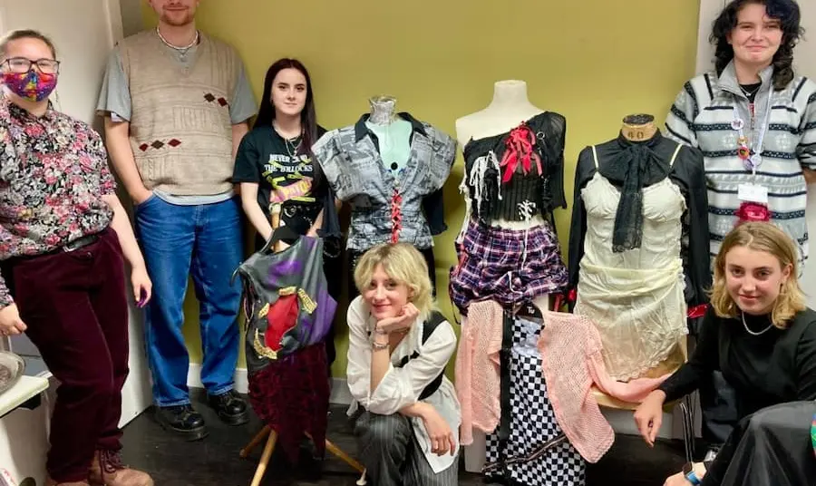 A group of people stand with Punk clothing on mannequins