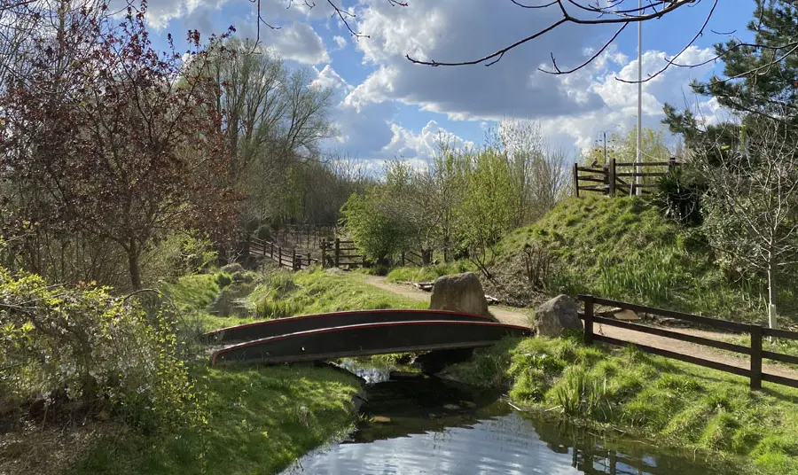 Railworld Wildlife Haven A pond with a bridge over it and footpath next to it on a sunny day