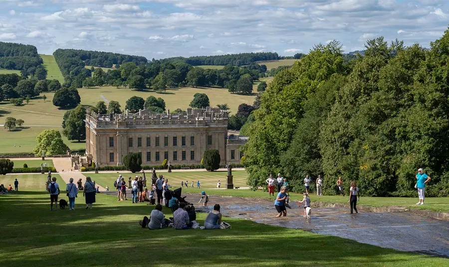 Visitors enjoy playing in the Chatsworth Cascade. Chatsworth House is in view in the distance.