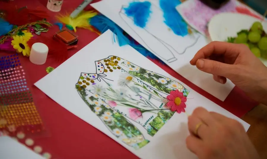 A person's hands working on a painting and collage of a Romanian Blouse