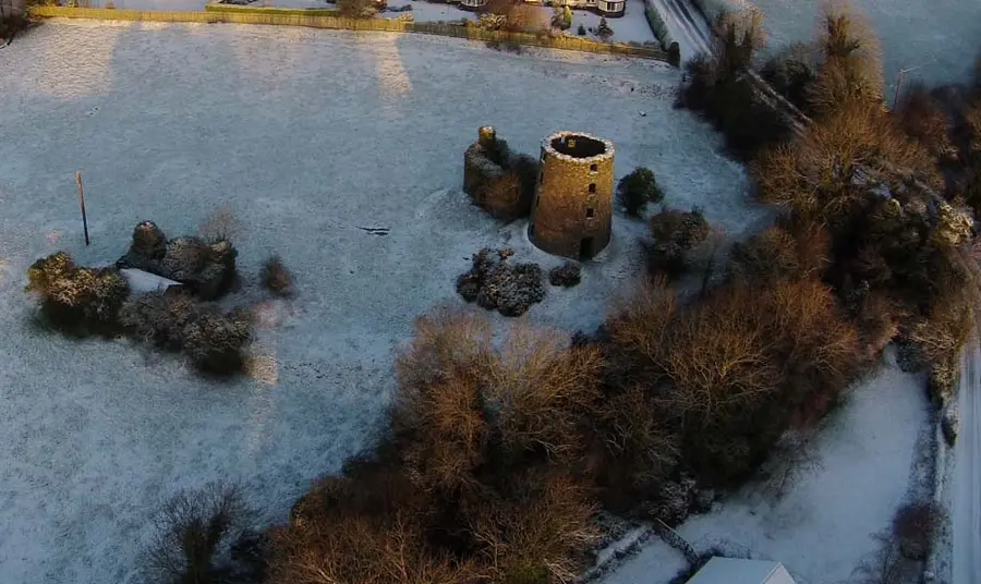 An aerial photo of a field with ruined mill buildings during winter
