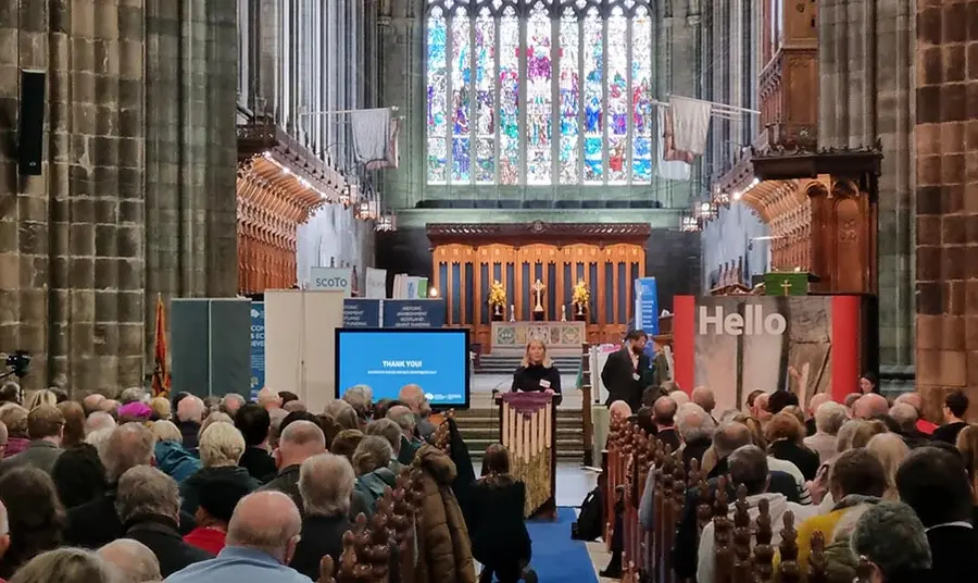 A person gives a speech inside a large church to a crowd of people seated in pews