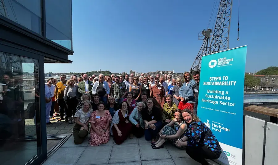 A large group of people are smiling for a group photo. There is a banner from Social Enterprise Academy in the photo.