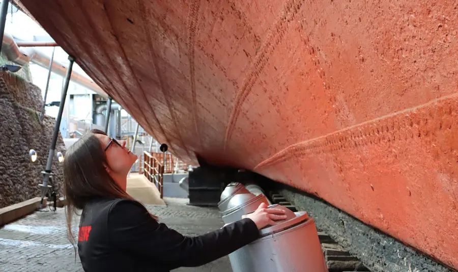 A person looks up at the ship's hull with the cooling system in the foreground