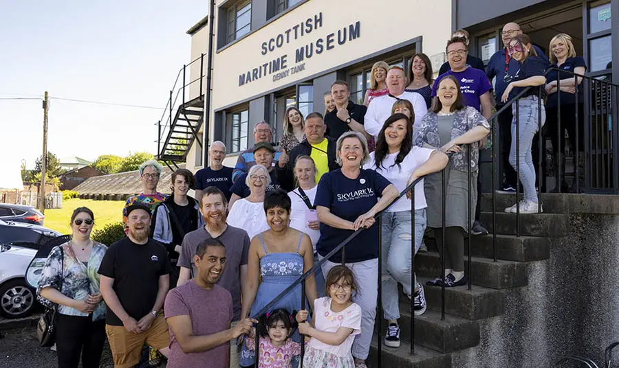 A large group of people from the Skylark IX team stand on the steps of the Scottish Maritime Museum