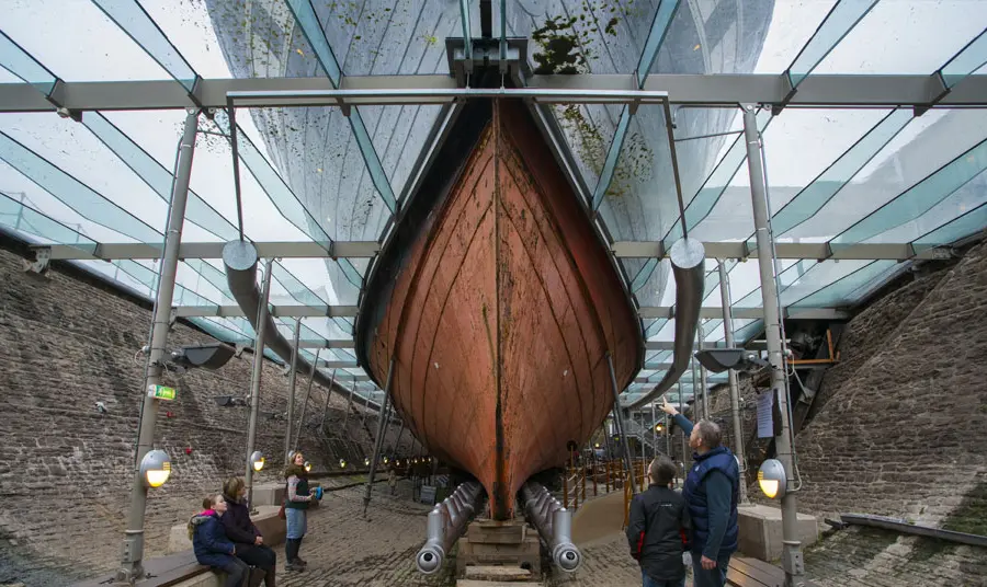 Visitors look up at the ship's hull, surrounded by the engineered conservation system