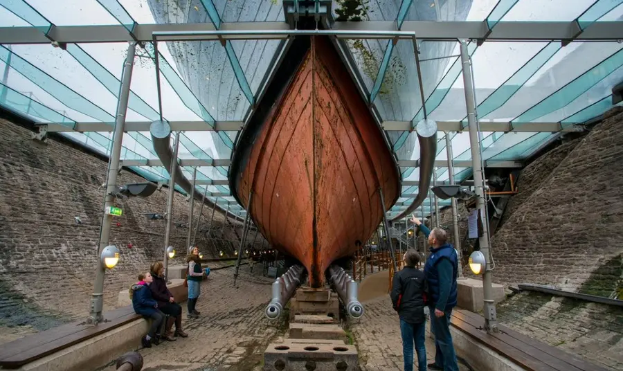 A view of the hull of SS Great Britain in dry dock, with visitors exploring.