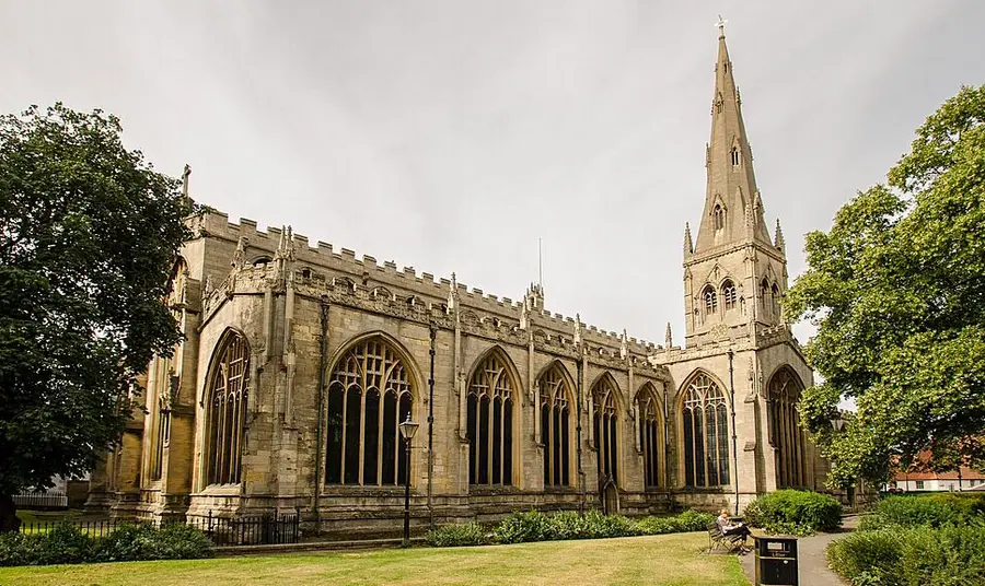 The exterior of a large church with a spire during summer