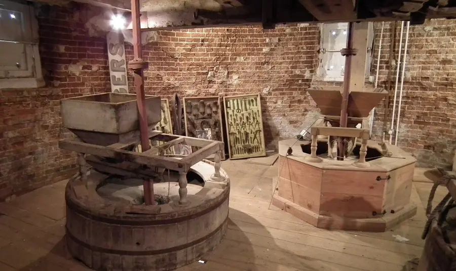 The 'stone floor' of the Mill's interior, showing the two grinding mill stones surrounded by equipment in glass display cases.