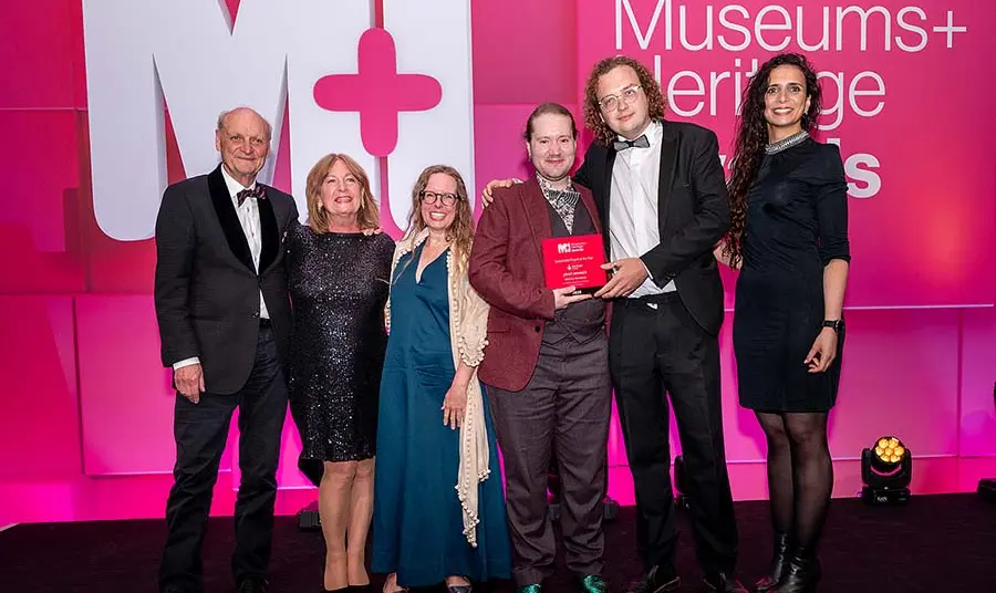 Representatives from the museum on stage holding their award.